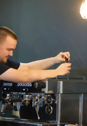 an engineer carrying out servicing on a commercial coffee machine