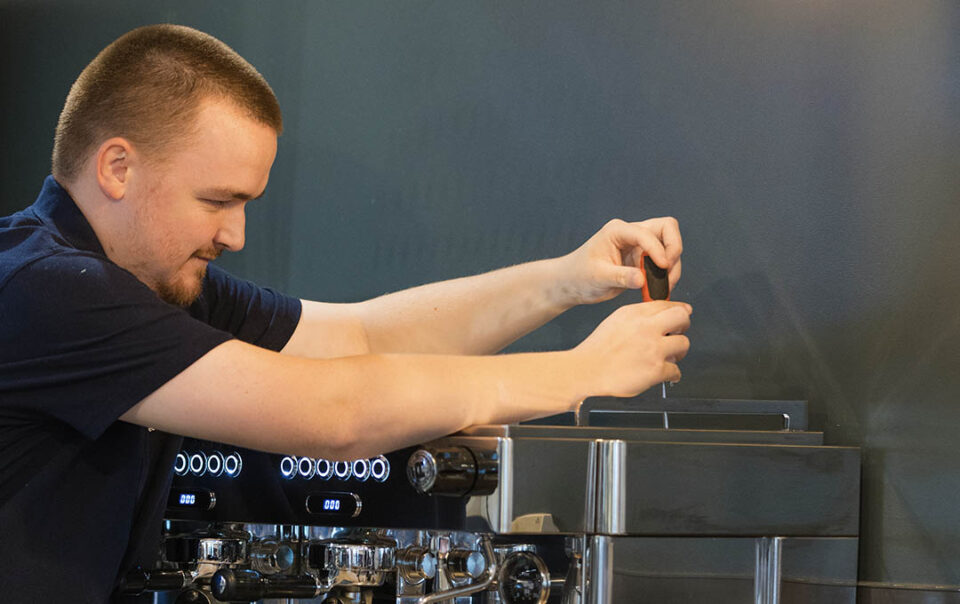 an engineer carrying out servicing on a commercial coffee machine