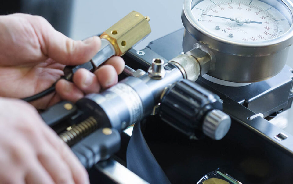 person testing coffee machine pressure with a pressure guage